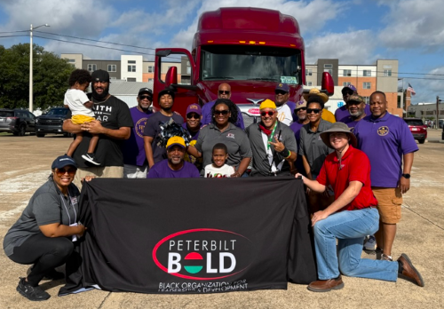 Peterbilt BOLD members and Peterbilt employees holding banner in front of a red Peterbilt Model 579