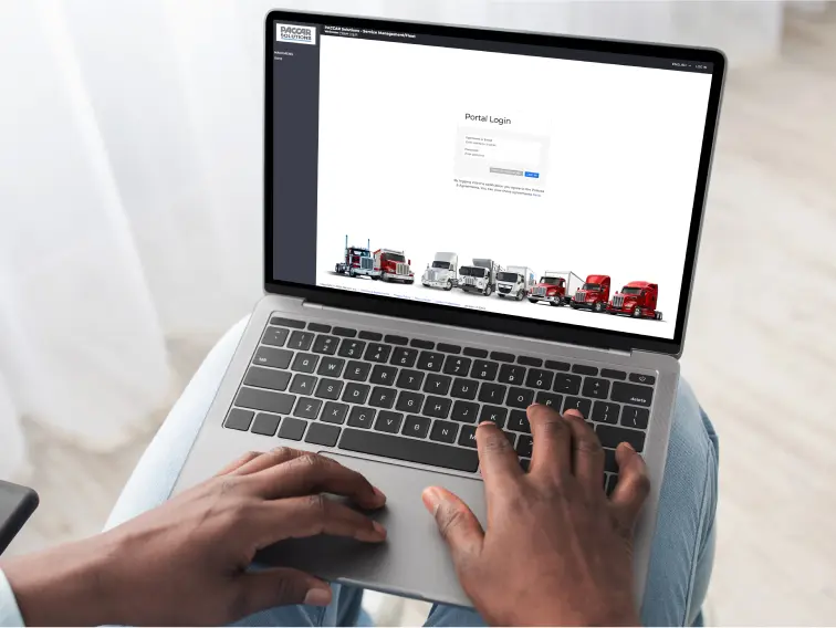 Person using laptop with PACCAR log in on screen
